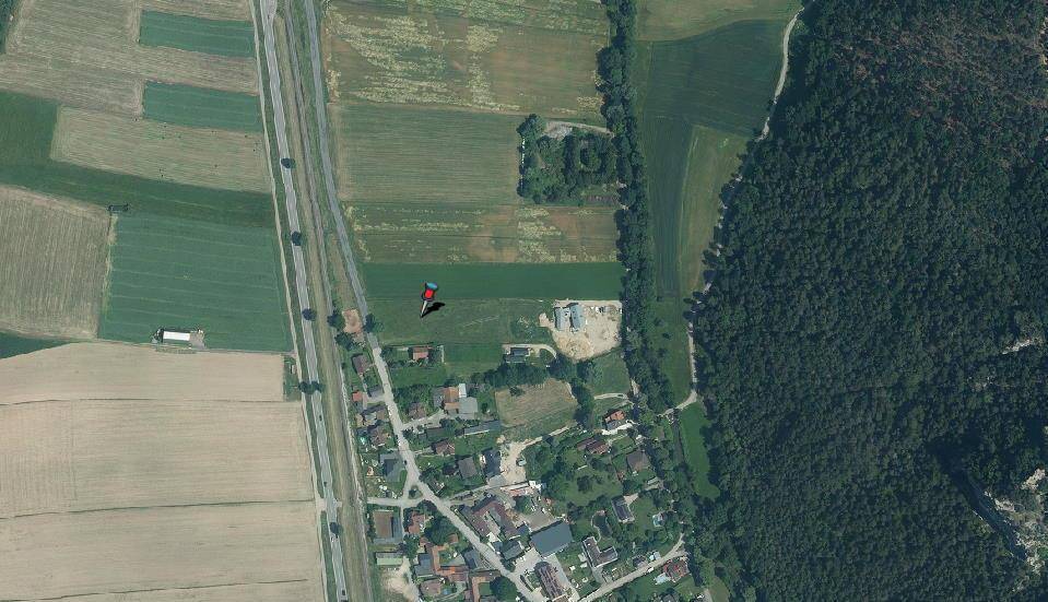 Luftaufnahme der ländlichen Umgebung mit Feldern, Wald und einer kleinen Siedlung.