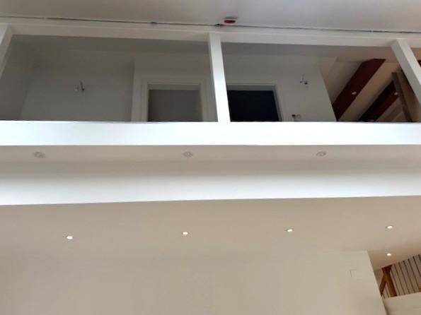 Galerieebene mit Geländer und Zugang zu weiteren Räumen, beleuchtet durch Deckenspots.