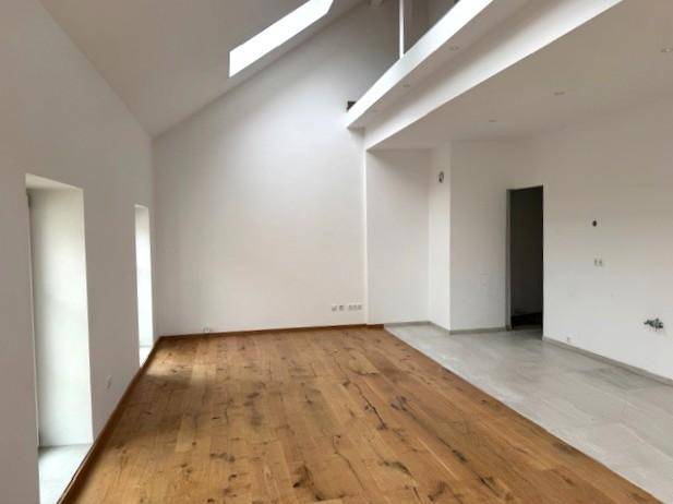 Heller Wohnbereich mit hohen Decken, Dachfenstern und einer Galerieebene, die viel Licht hereinlässt.