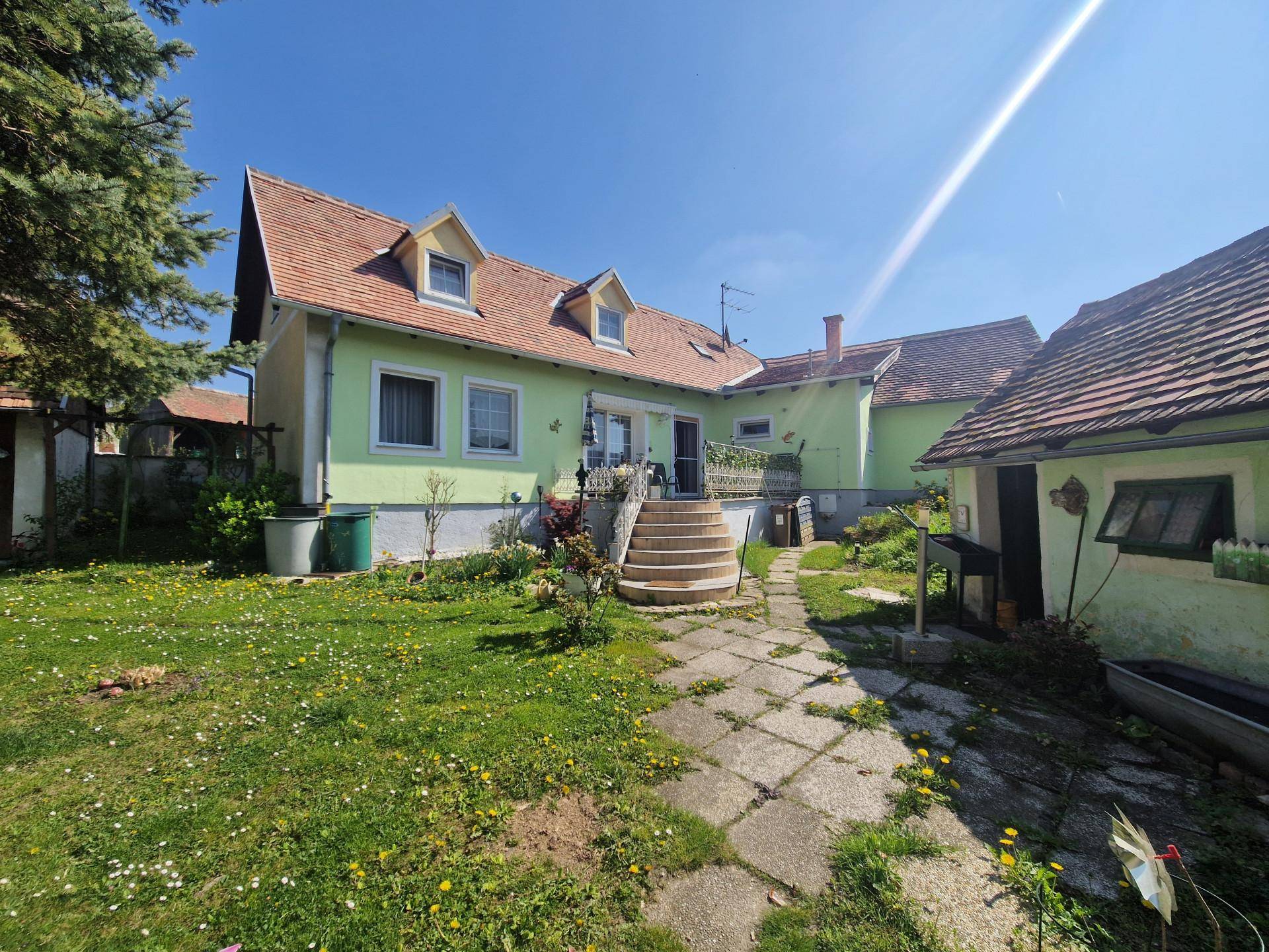 Rückseite des Hauses mit Zugang zum Garten und einem gepflasterten Weg durch die Rasenfläche.