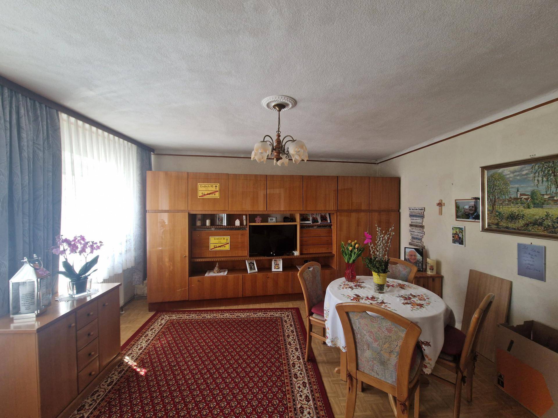 Essbereich mit großem Holzschrank, Esstisch und Teppichboden in einem traditionellen Ambiente.