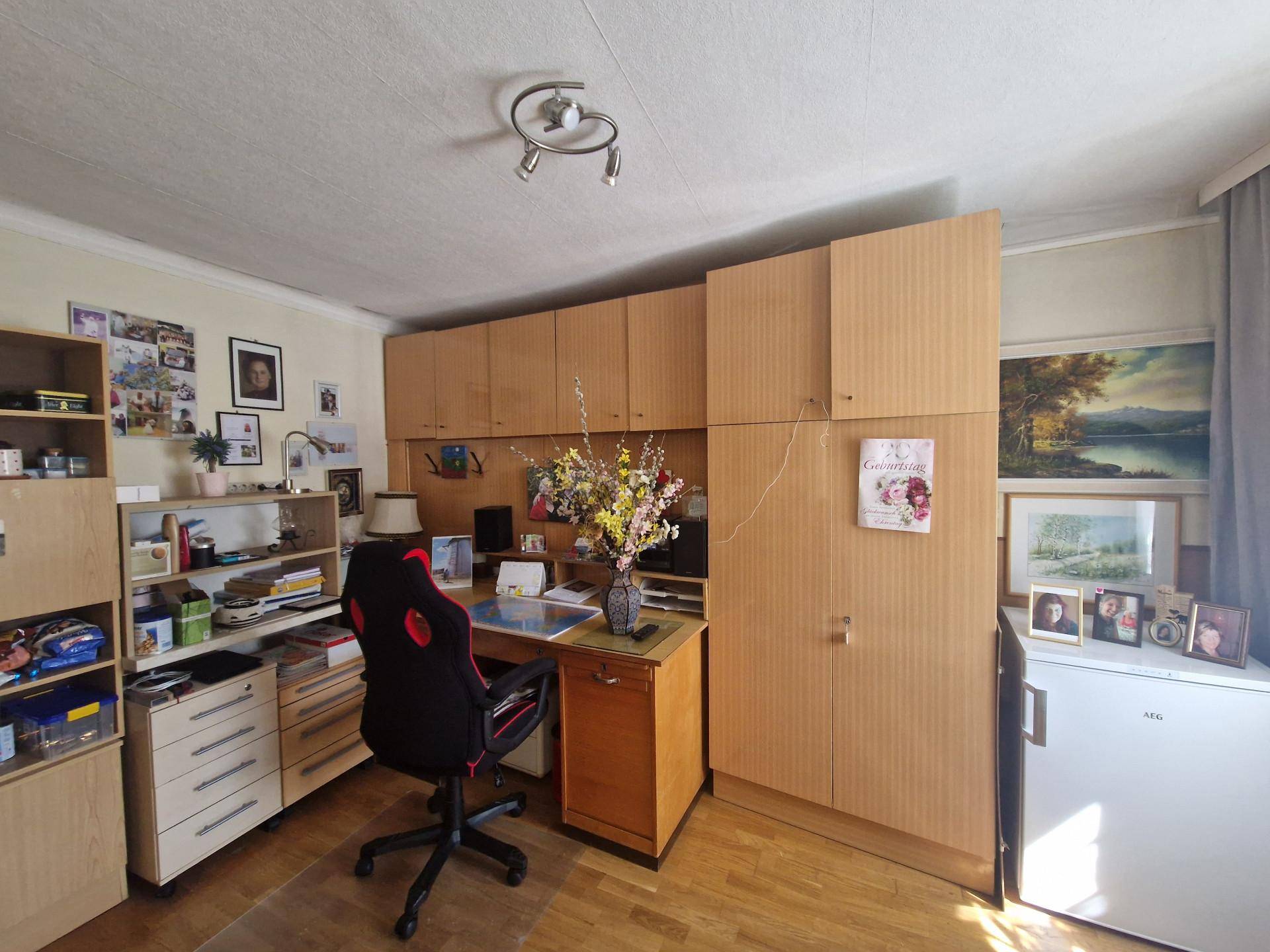 Arbeitszimmer mit Schreibtisch, Bürostuhl und vielen Holzschränken für Stauraum.