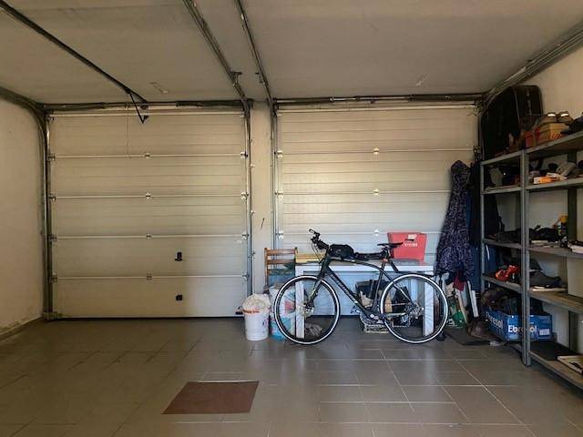 Saubere Doppelgarage mit zwei Rolltoren, Fliesenboden und Regalen für Lagerung.