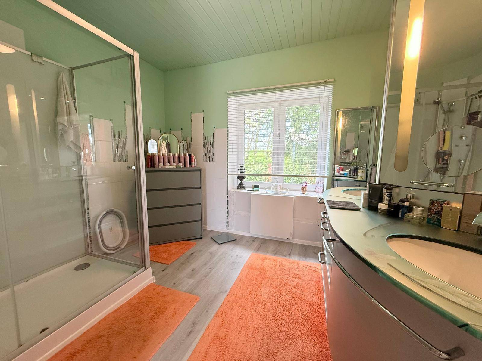 Geräumiges Badezimmer mit Dusche, Doppelwaschbecken und Fenster.