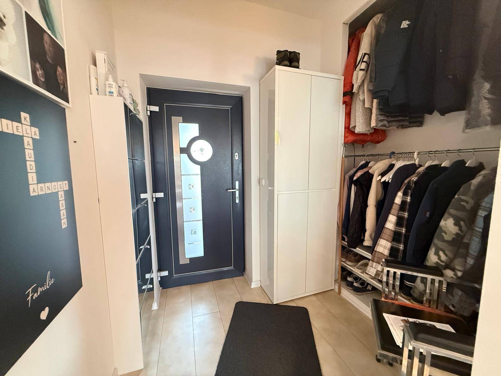 Eingangsbereich mit Garderobe, Schränken und moderner Eingangstür.