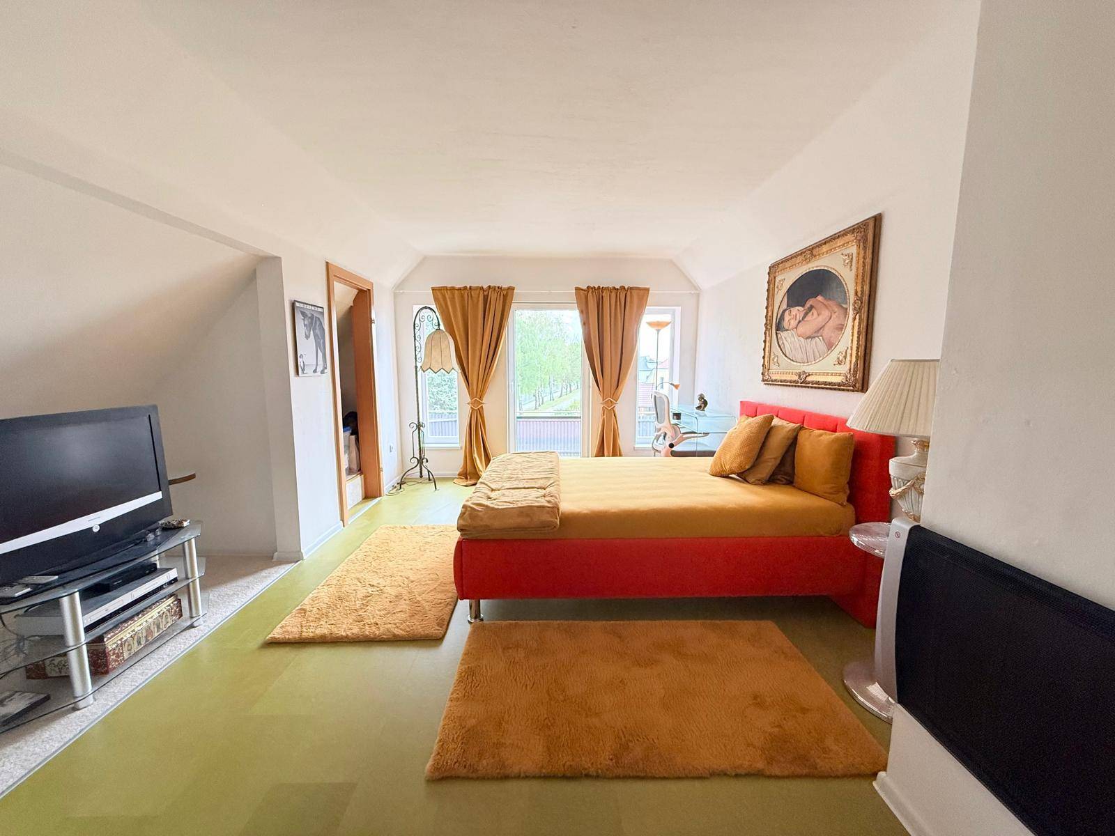 Gemütliches Schlafzimmer im Dachgeschoss mit schrägen Wänden und Blick ins Grüne.