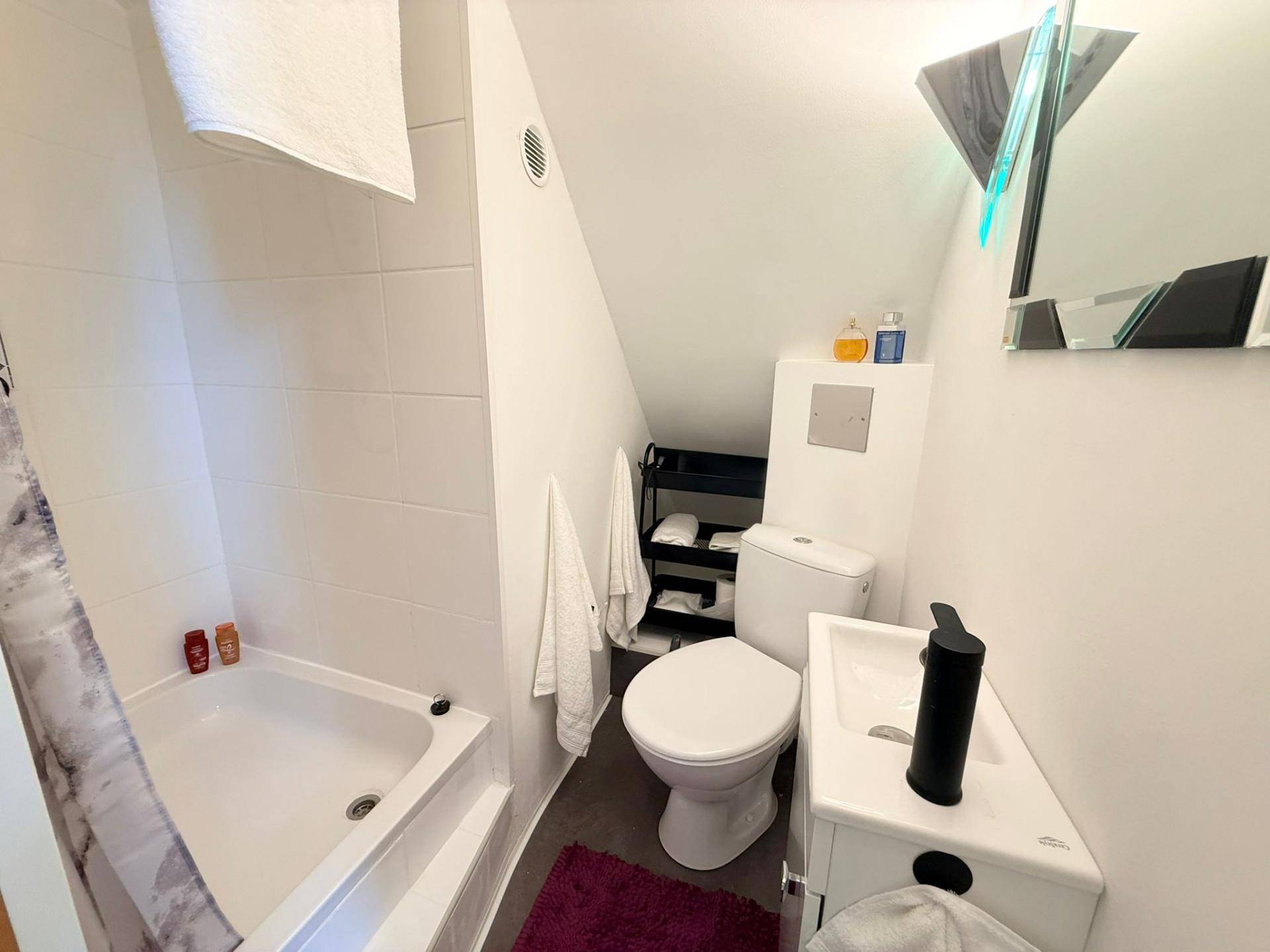 Kleines Badezimmer im Dachgeschoss mit Dusche, WC und Waschbecken.