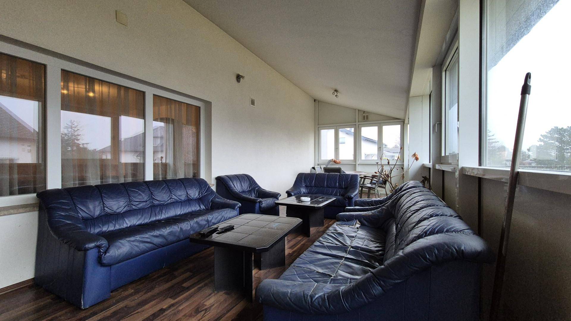 Verglaste Loggia mit blauen Ledersofas und Holzboden, ideal zum Entspannen.