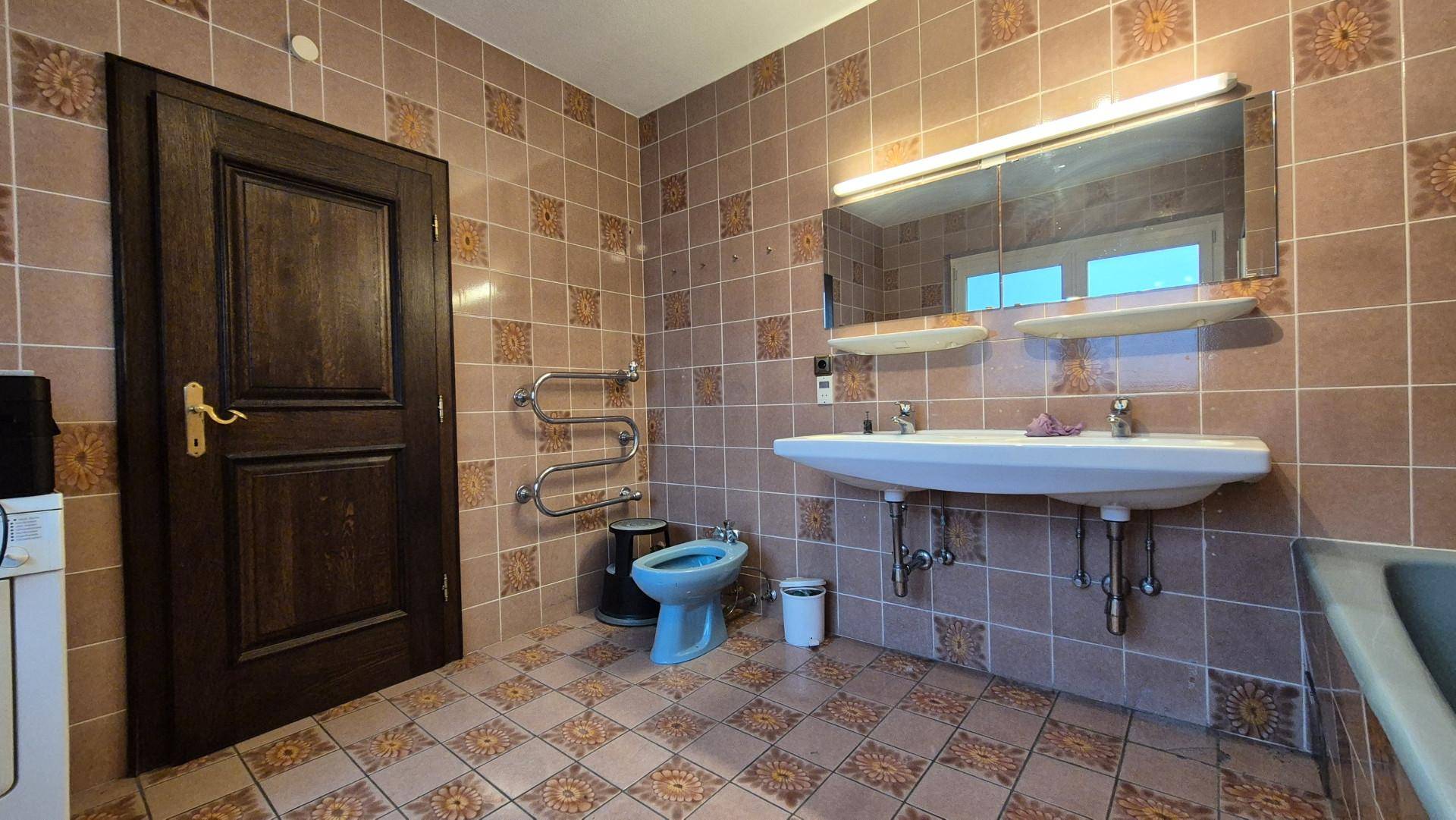 Badezimmer mit Doppelwaschbecken, Bidet und gemusterten Fliesen im Retro-Stil.