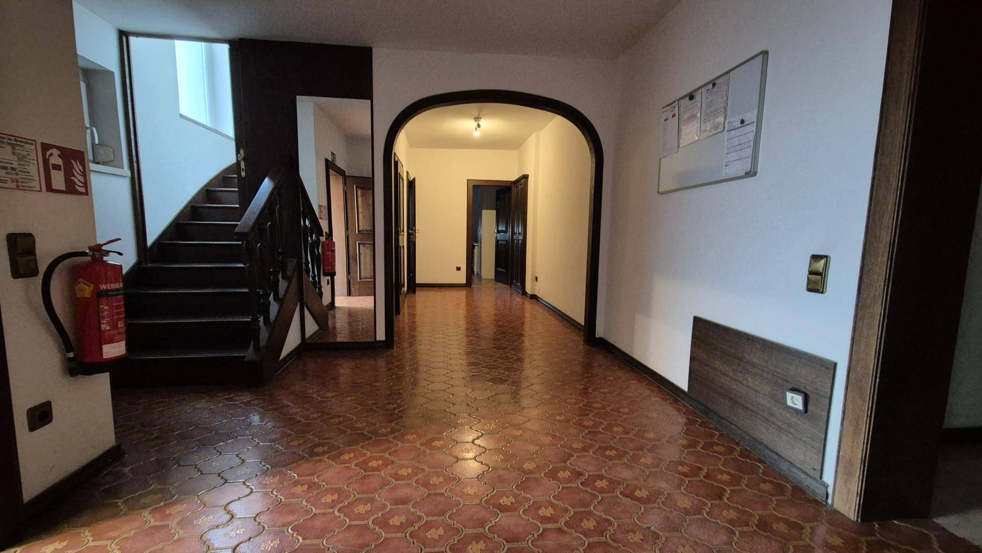 Eingangsbereich mit gefliestem Boden, Treppe und einem Durchgang zu weiteren Räumen.