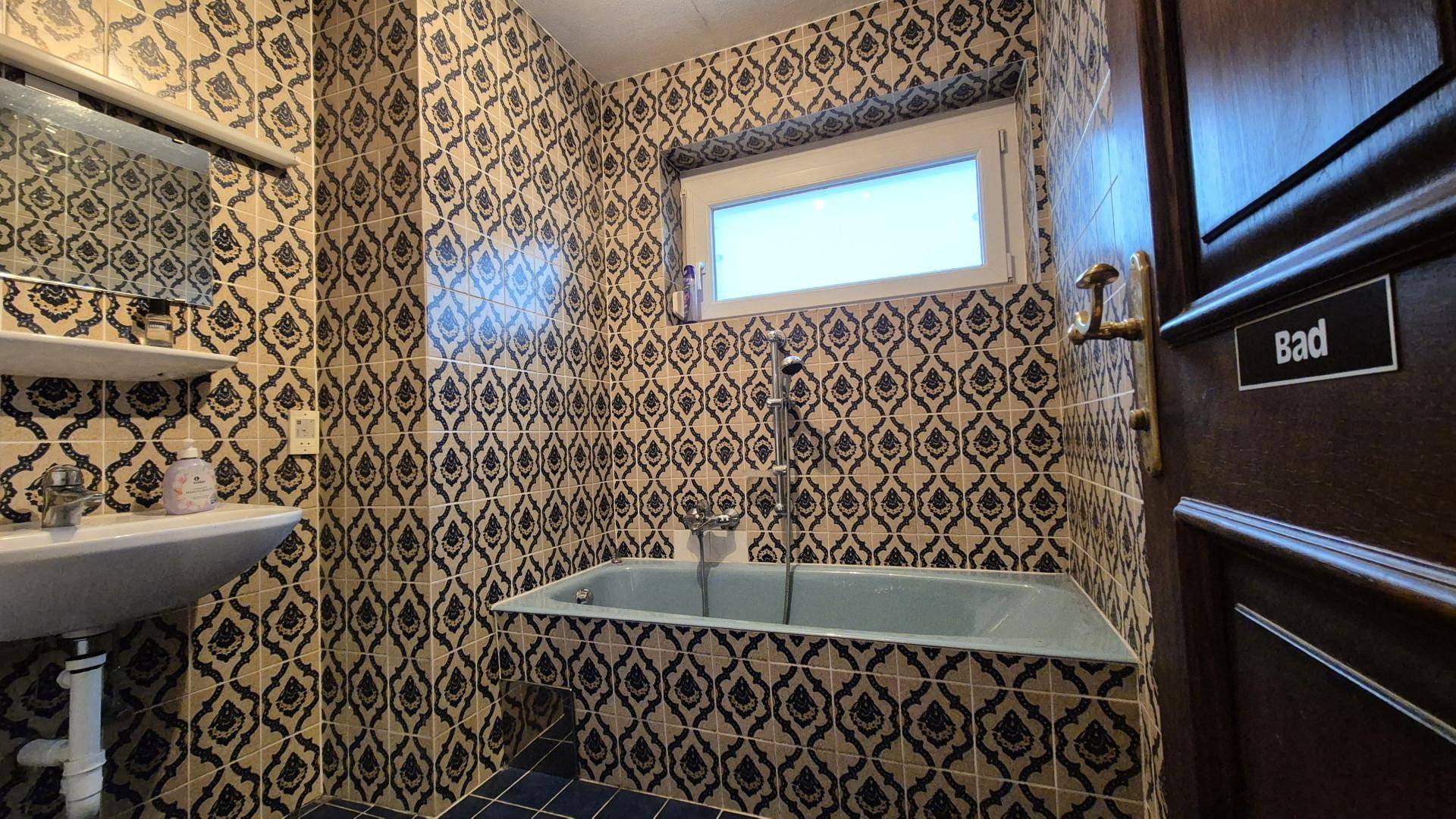 Badezimmer mit Badewanne und auffälligen gemusterten Fliesen im Retro-Stil.