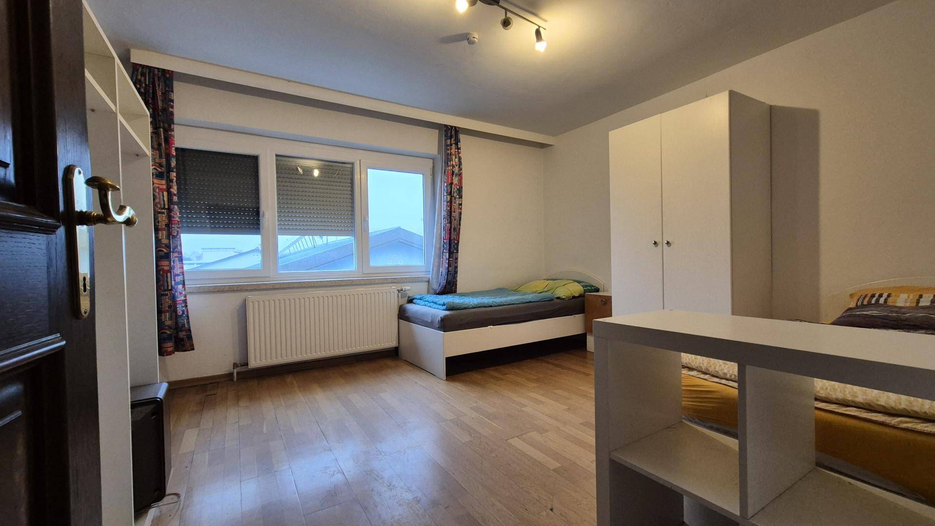 Schlafzimmer mit zwei Einzelbetten, Holzboden und einem großen Kleiderschrank.