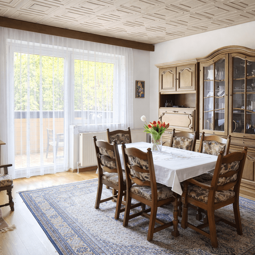 Gemütlicher Essbereich mit Holztisch, Stühlen, Teppich und Zugang zum Balkon.