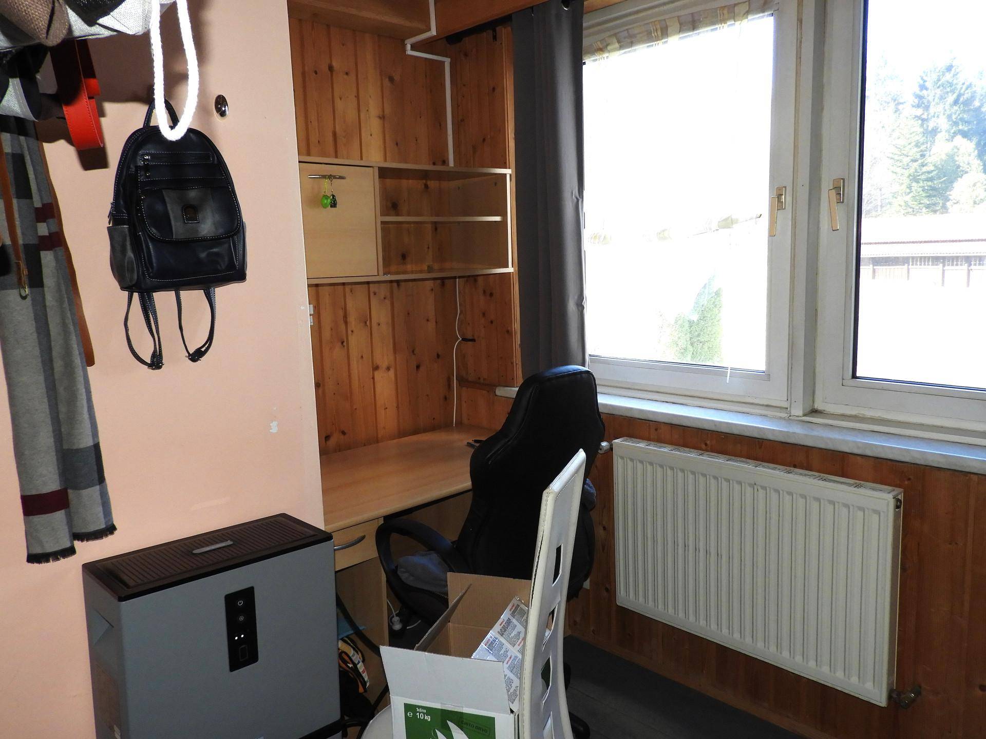Kleines Zimmer mit Holzvertäfelung, Schreibtisch und Fenster.