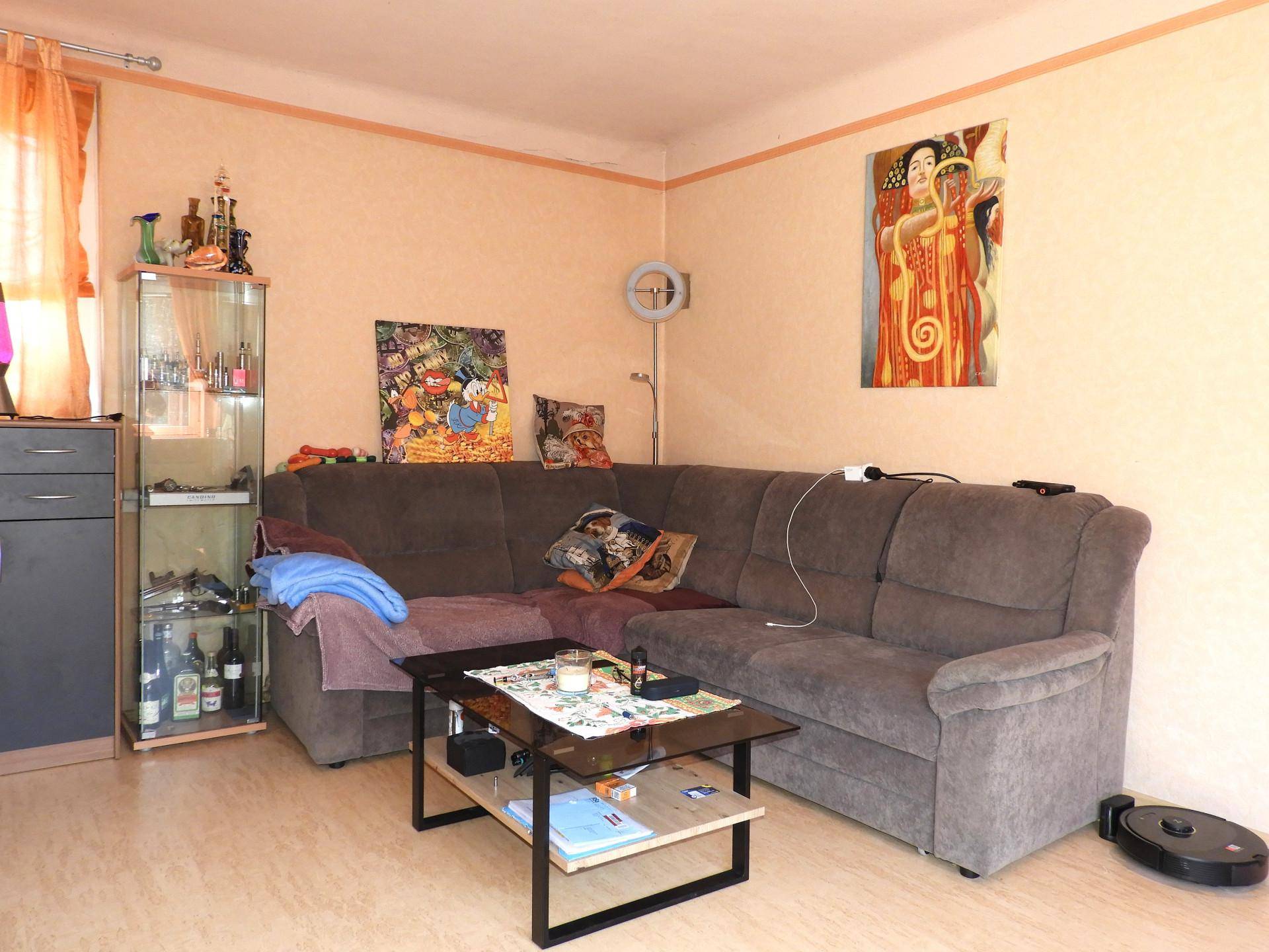 Geräumiges Wohnzimmer mit beigem Sofa, Couchtisch und Wanddekoration.