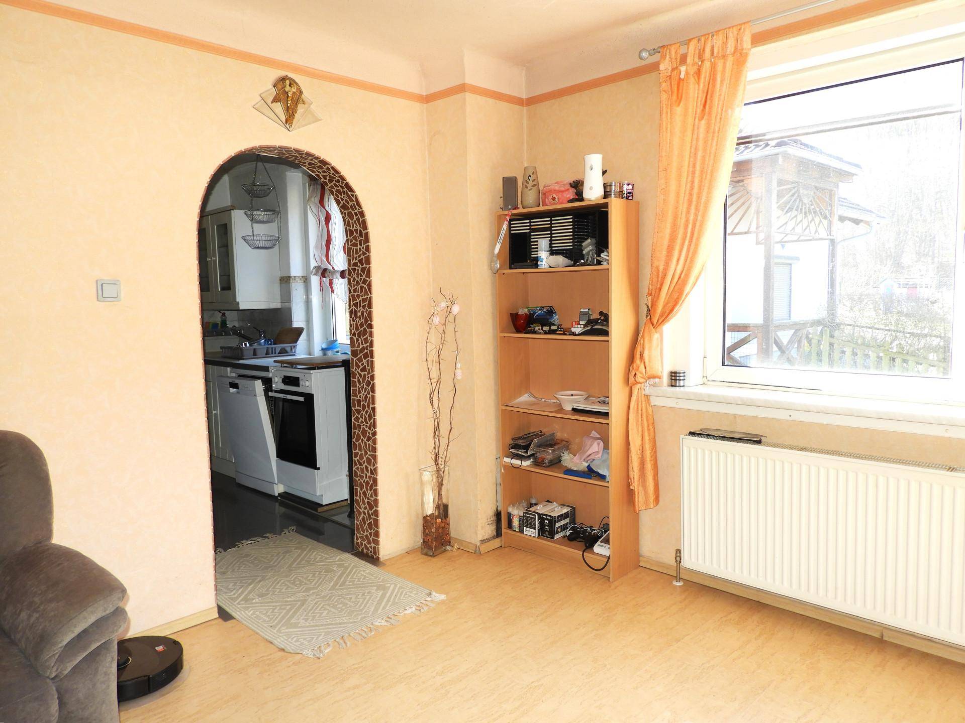 Wohnzimmer mit Laminatboden und einem Durchgang zur Küche.