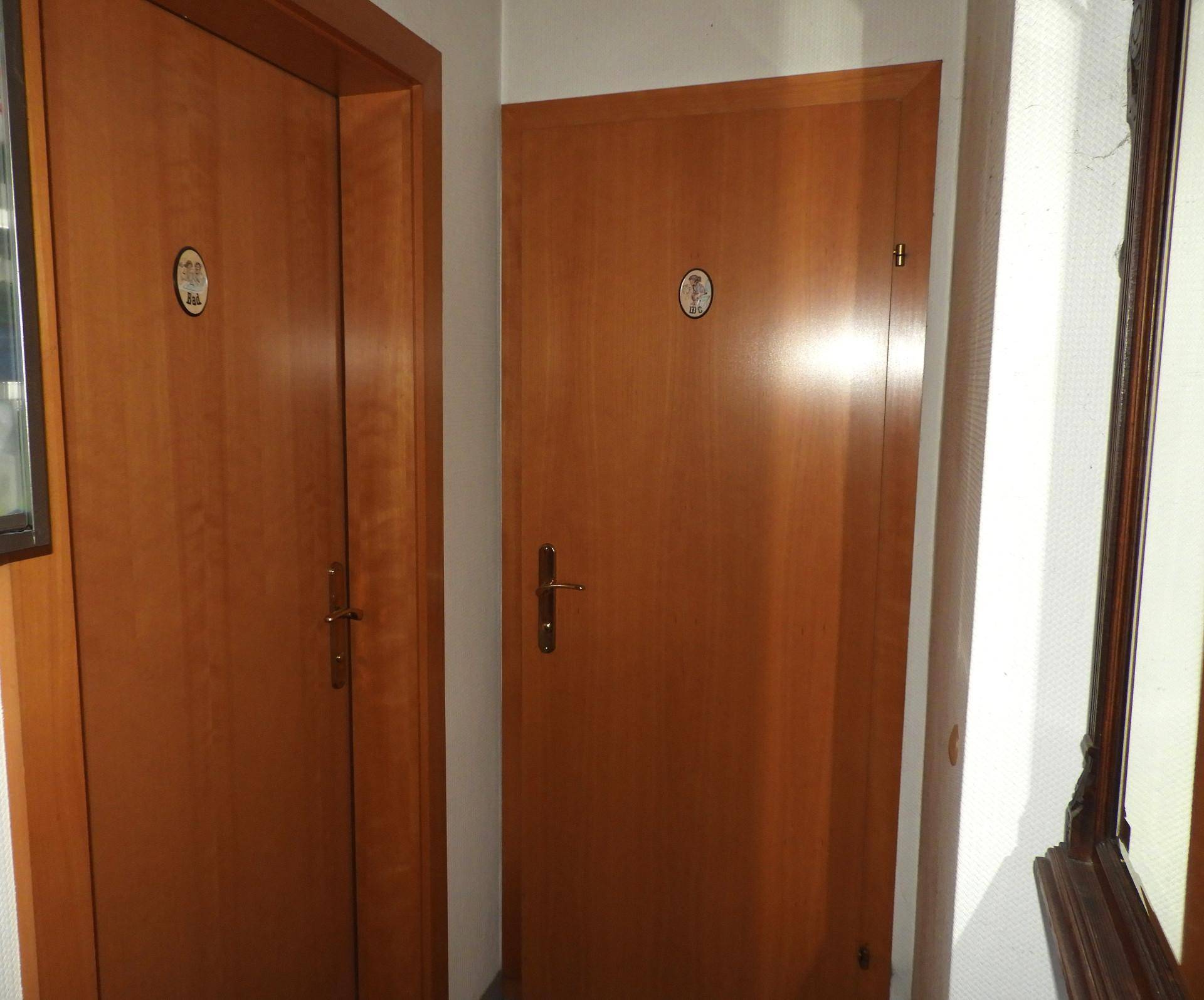 Flur mit zwei Holztüren und einem Spiegel an der Wand.