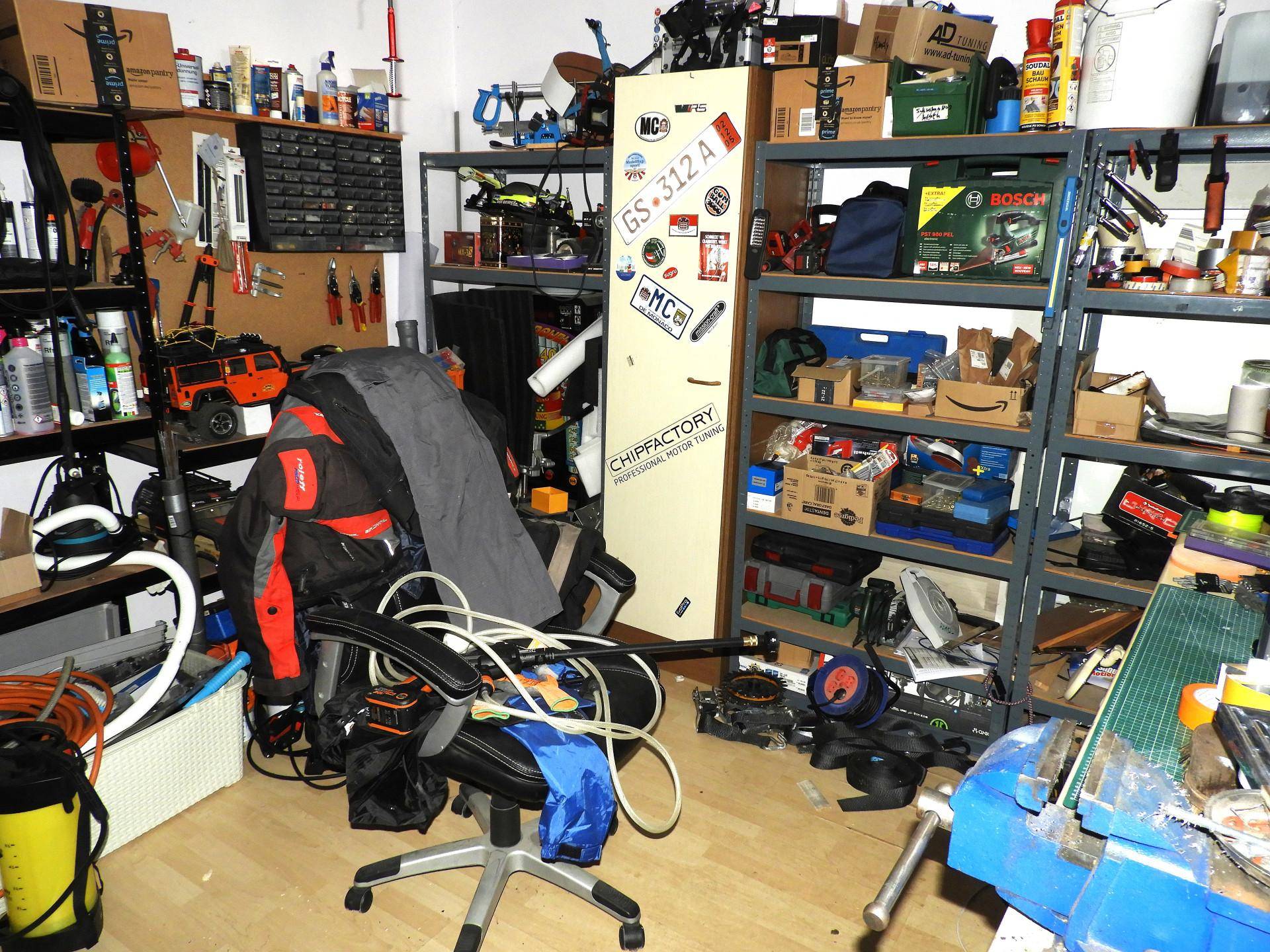 Werkstattraum mit Regalen voller Werkzeuge und Materialien sowie einem Arbeitstisch.