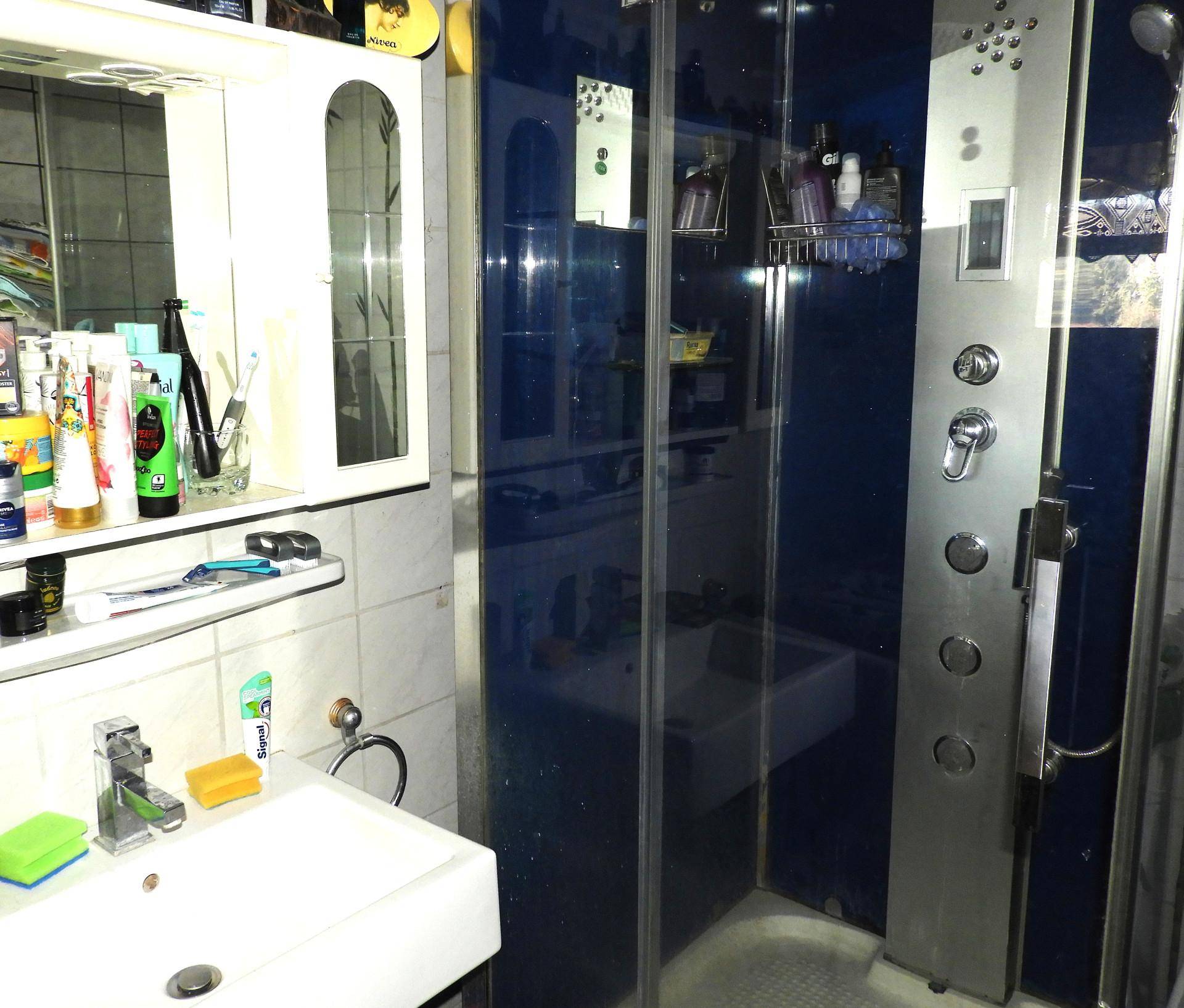 Badezimmer mit Duschkabine, Waschbecken und Spiegelschrank.