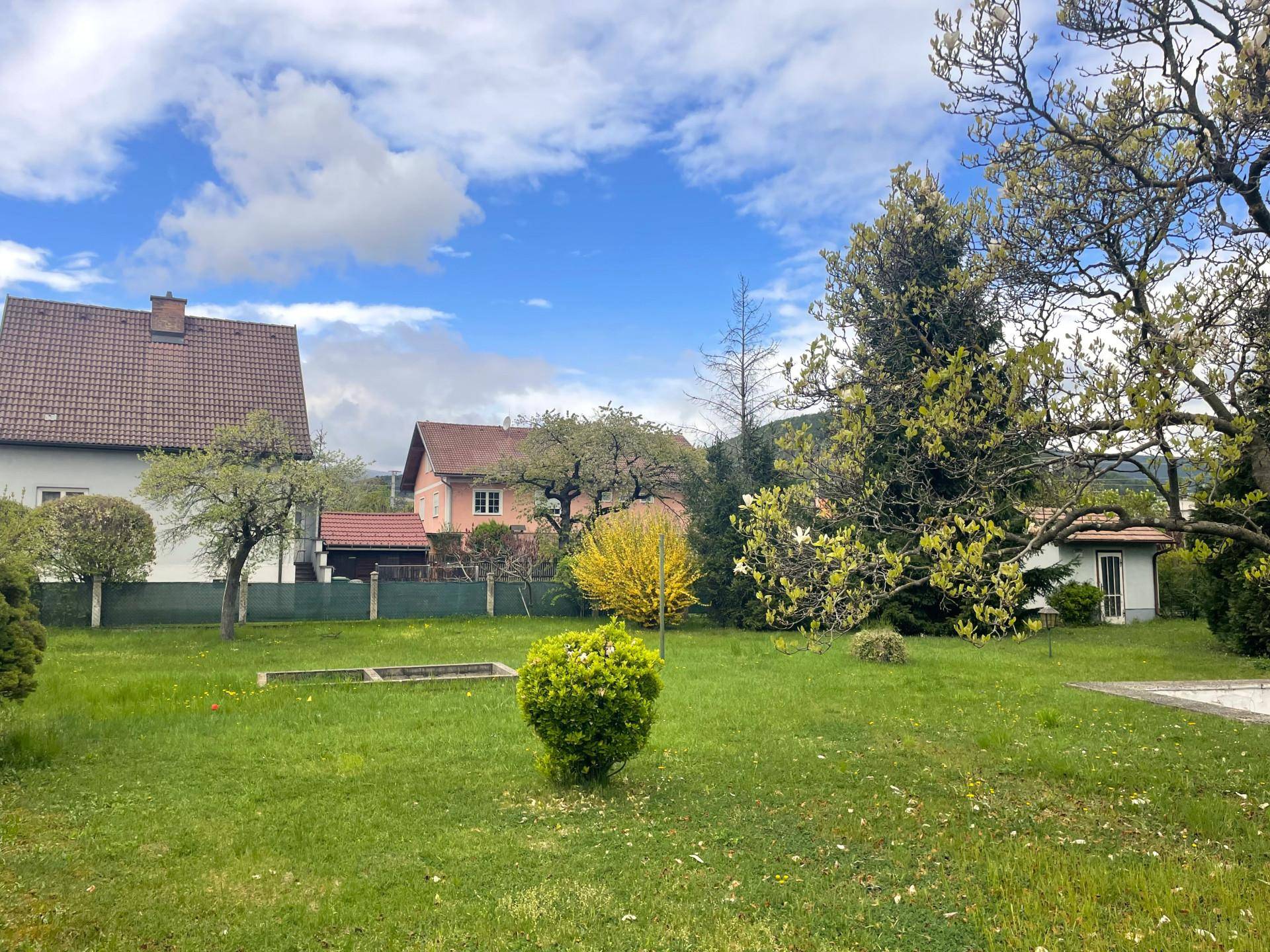 Weitläufiger Garten mit viel Grün, Bäumen und Blick auf die umliegenden Häuser.