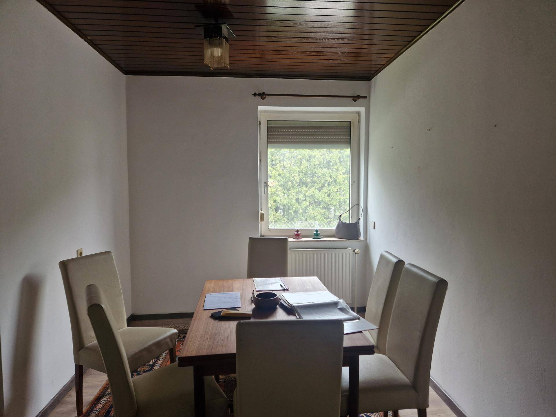 Gemütlicher Essbereich mit Holztisch, Stühlen und Fenster, das viel Tageslicht hereinlässt.