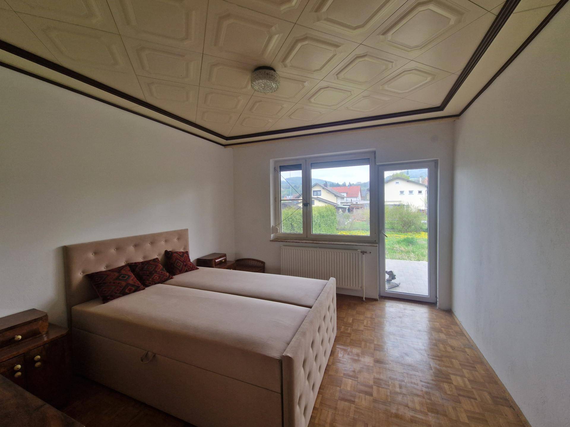 Schlafzimmer mit Doppelbett, Parkettboden und direktem Zugang zu einem Außenbereich.