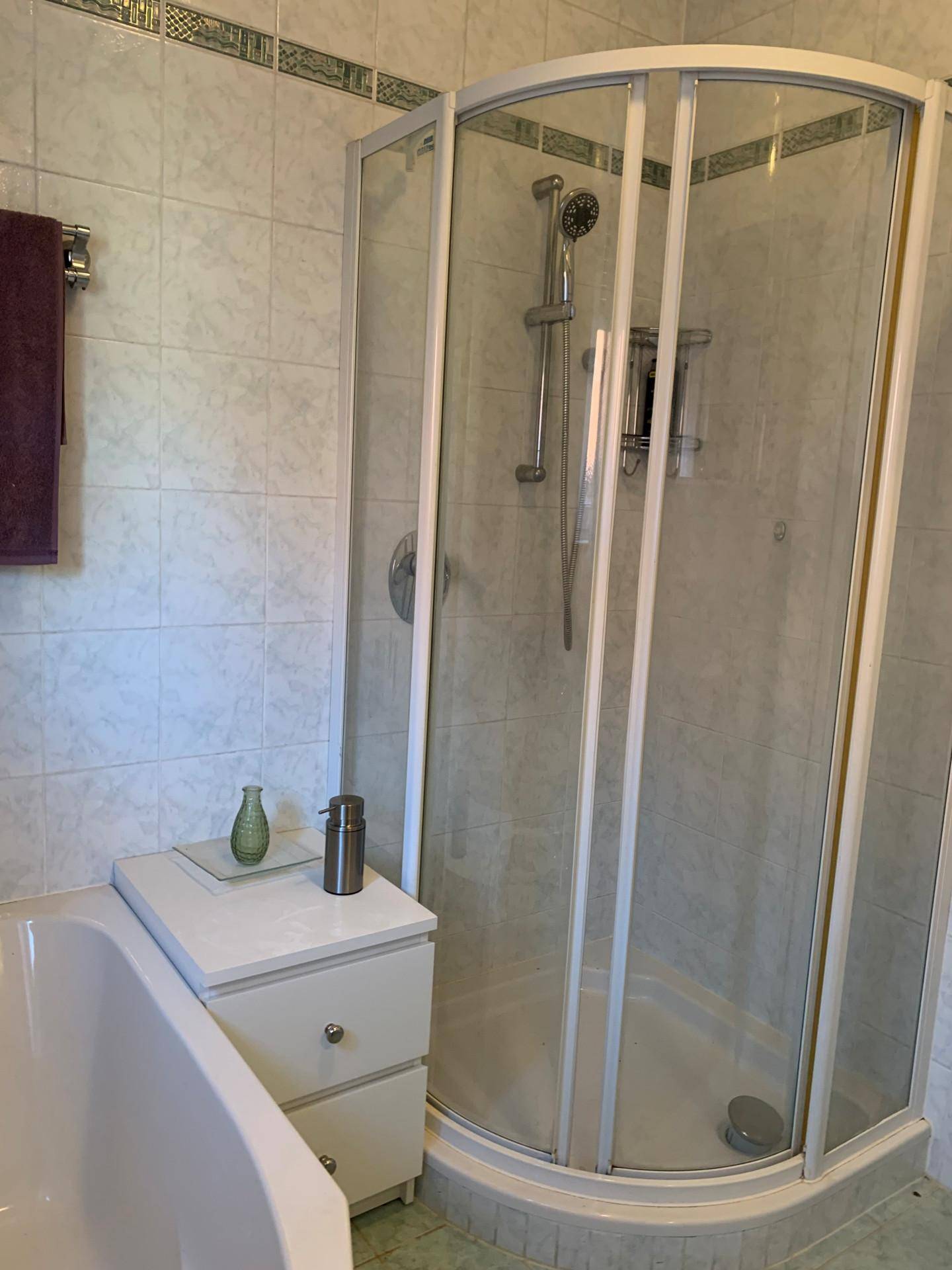 Badezimmer mit Duschkabine und Badewanne, hell gefliest und funktional eingerichtet.
