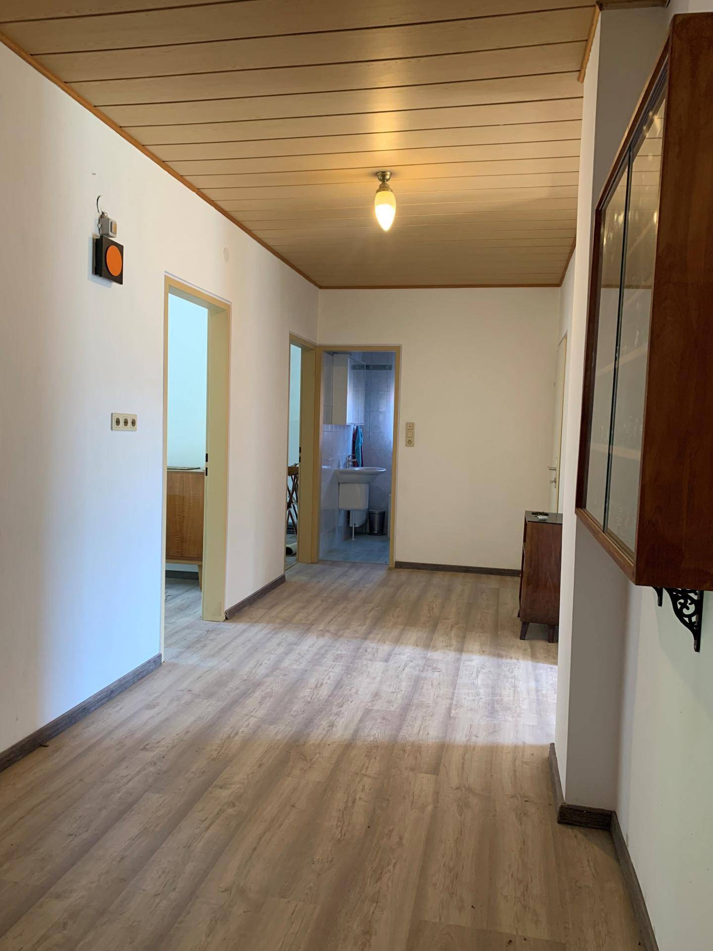 Heller Flur mit Holzdecke und Laminatboden, verbindet verschiedene Räume im Haus.