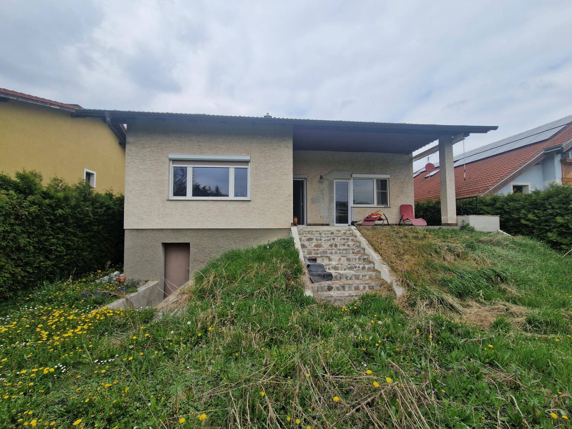 Rückansicht des Hauses mit Zugang zum Garten und einer Treppe auf einem Hanggrundstück.