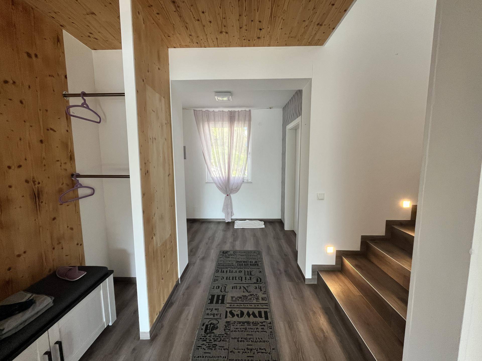 Heller Flur mit Holzdecke, integrierter Garderobe und Treppe zum Obergeschoss.