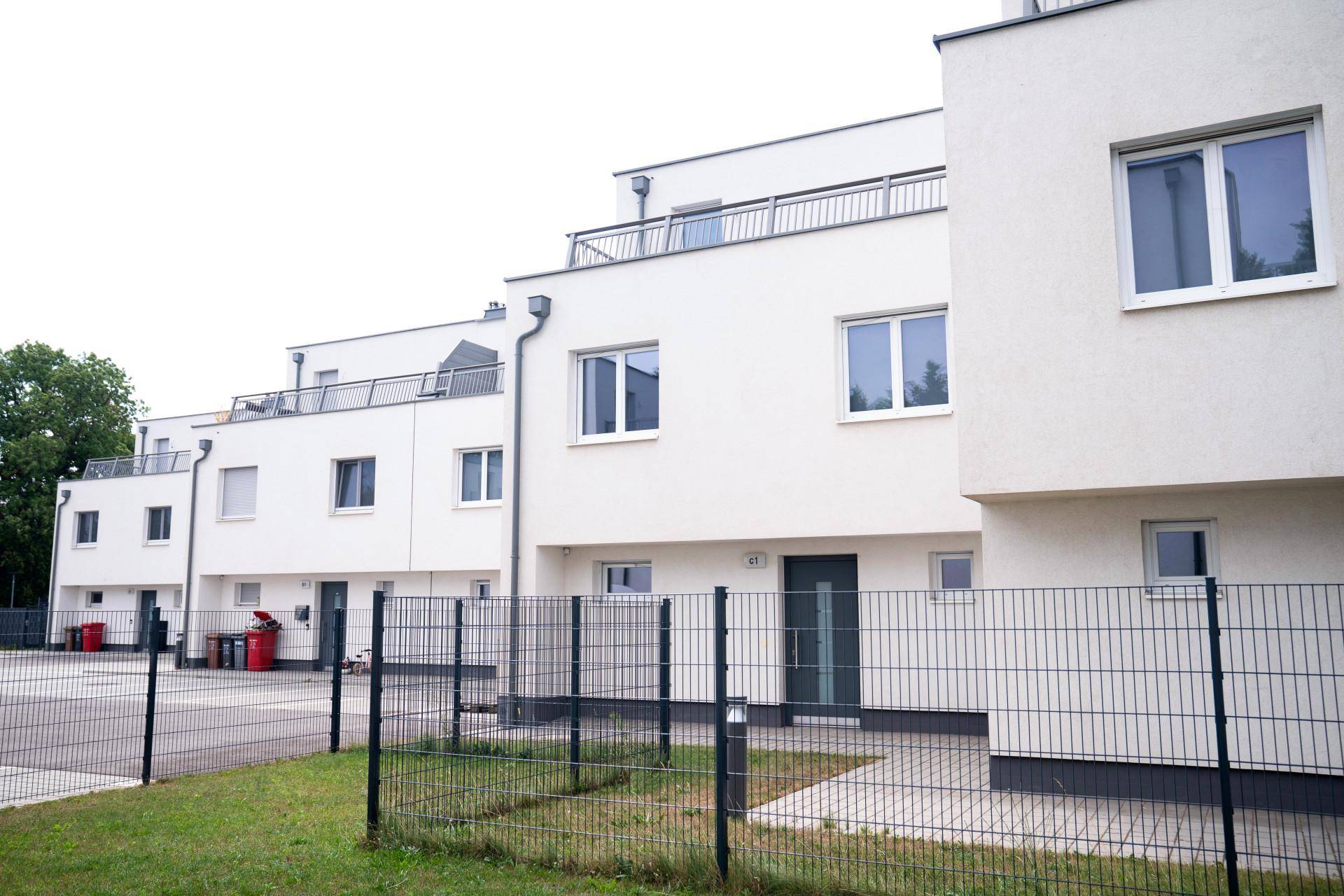 Moderne Reihenhäuser mit weißer Fassade, Flachdächern und kleinen Vorgärten.