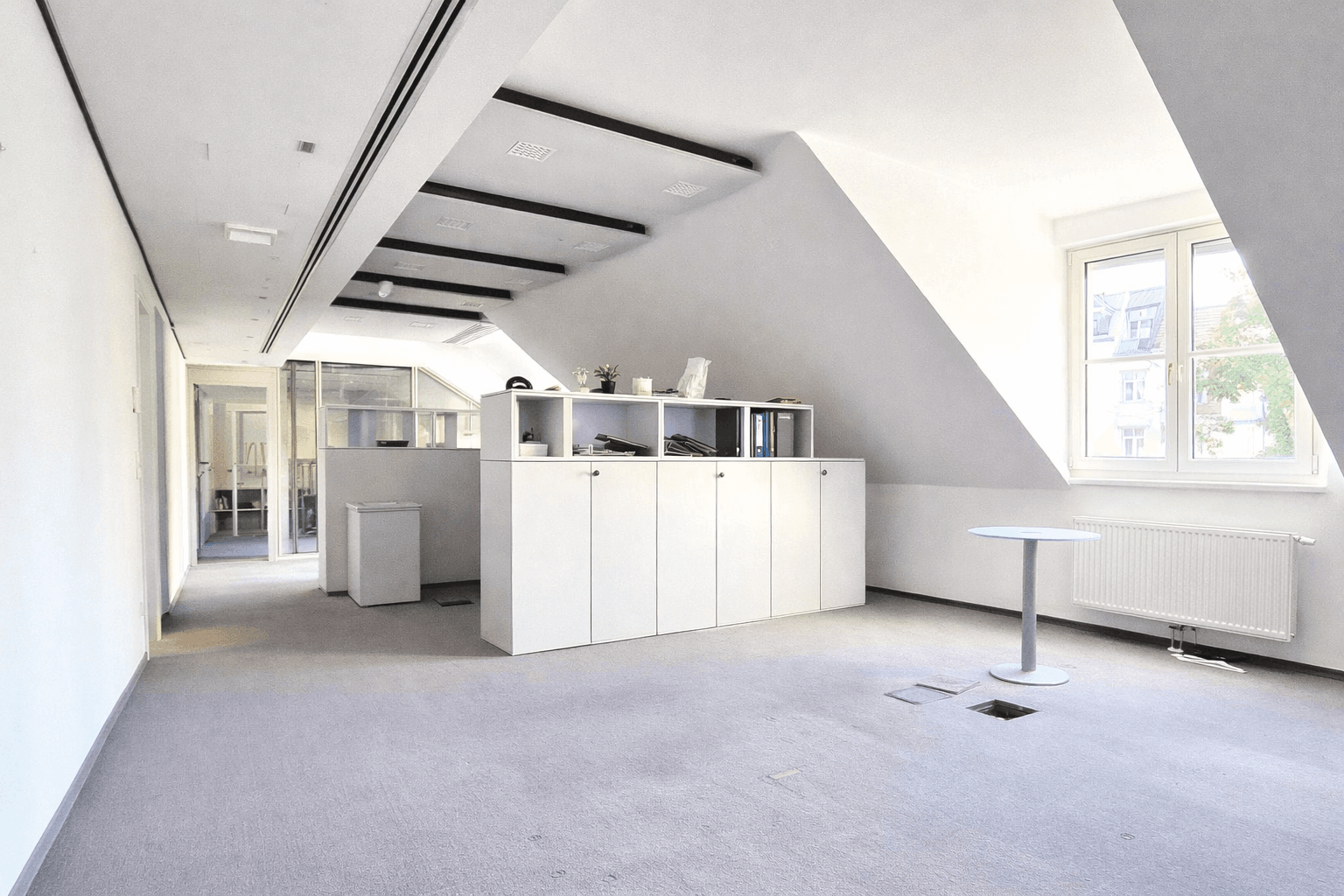 Büro mit Teppichboden, Einbauschränken und schrägen Wänden, ideal für flexible Arbeitsbereiche.