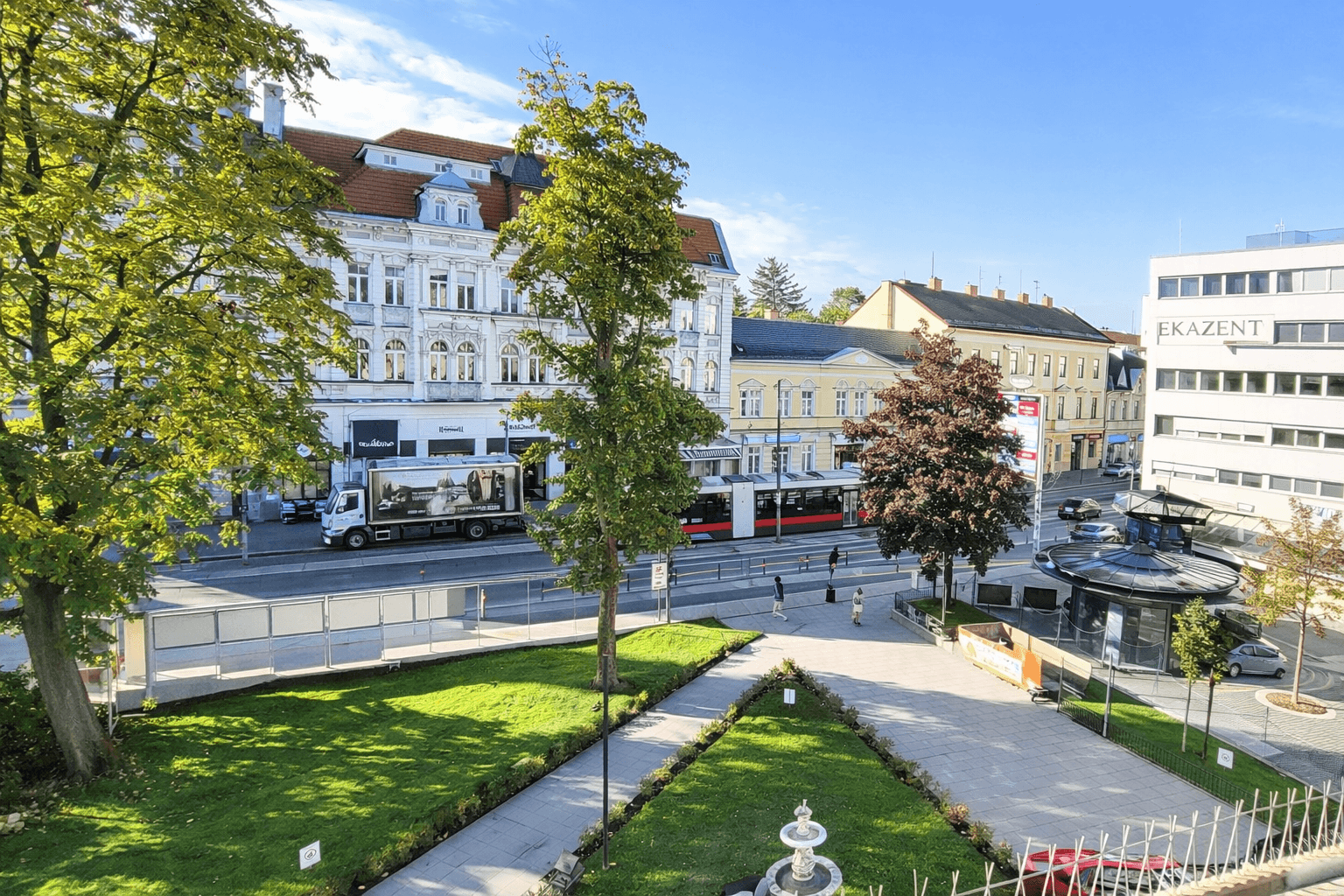 Blick auf die belebte Straße mit historischen Gebäuden, Bäumen und öffentlichen Verkehrsmitteln.