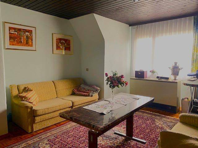 Wohnzimmer mit gelbem Sofa, Couchtisch mit Marmorplatte und einem gemusterten Teppich.