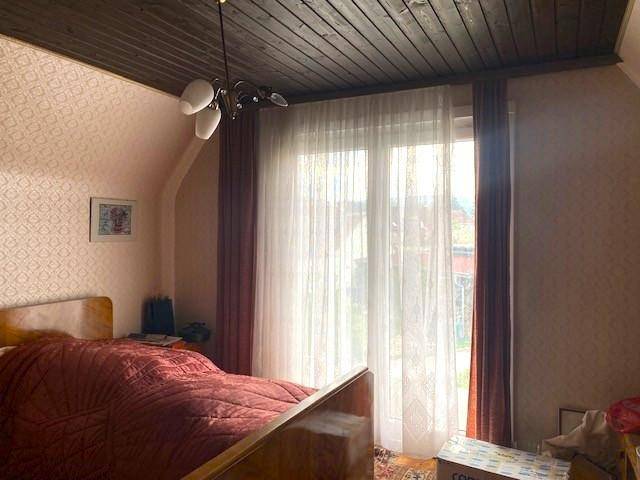 Schlafzimmer mit Bett, großem Fenster mit Vorhängen und einer Dachschräge.