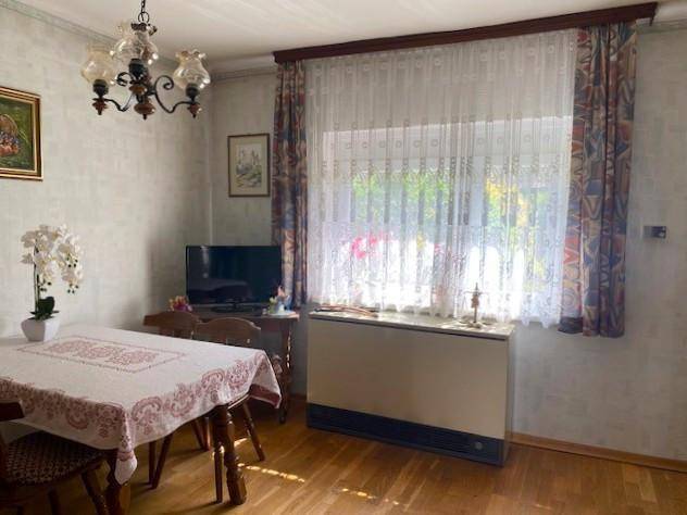 Essbereich mit Holztisch, Stühlen und einem großen Fenster mit Vorhängen.