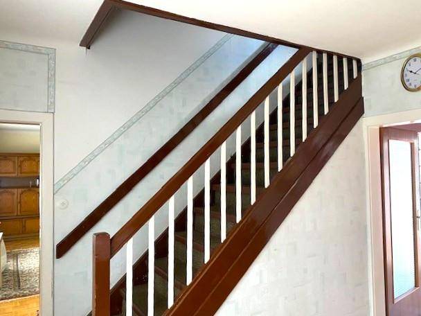 Treppenhaus mit Holzgeländer und weißen Balustern, das in die obere Etage führt.