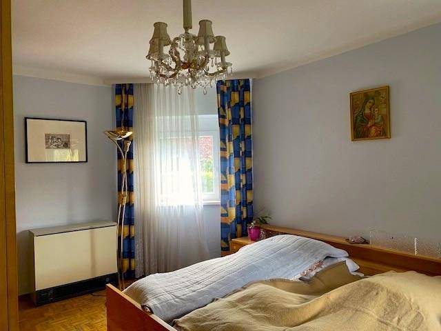 Schlafzimmer mit zwei Betten, einem Kronleuchter und einem Fenster mit farbenfrohen Vorhängen.