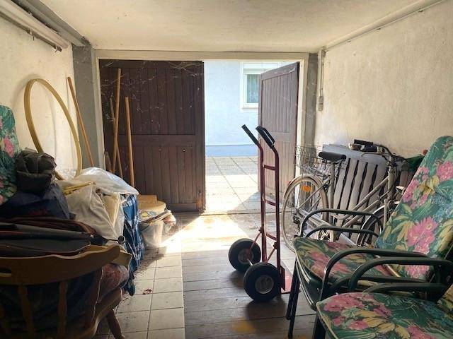 Garage oder Lagerbereich mit offener Tür nach draußen und verschiedenen Gegenständen.