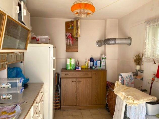 Hauswirtschaftsraum oder Waschküche mit Kühlschrank, Schränken und einem Fenster.