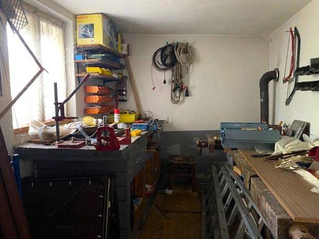 Werkstatt oder Hobbyraum mit Werkbank, Werkzeugen und Regalen für Materialien.