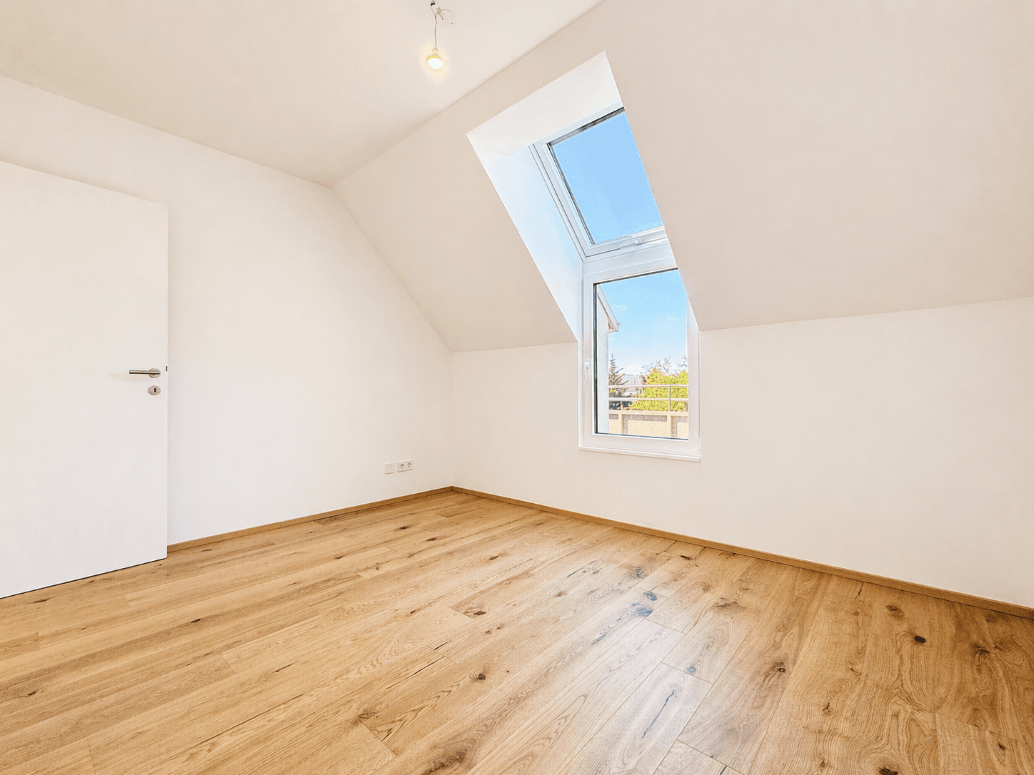 Helles Schlafzimmer im Dachgeschoss mit schrägen Wänden und großem Dachfenster für viel Tageslicht.