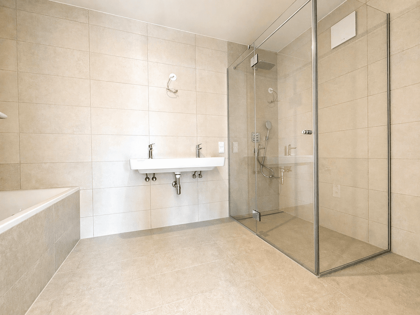 Modernes Badezimmer mit beigefarbenen Fliesen, Doppelwaschbecken, begehbarer Dusche und Badewanne.