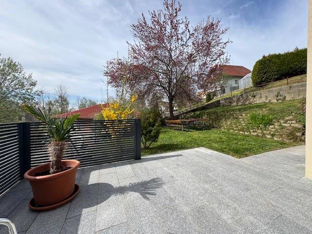 Geräumige Terrasse mit Blick auf den Garten und die umliegende grüne Landschaft.