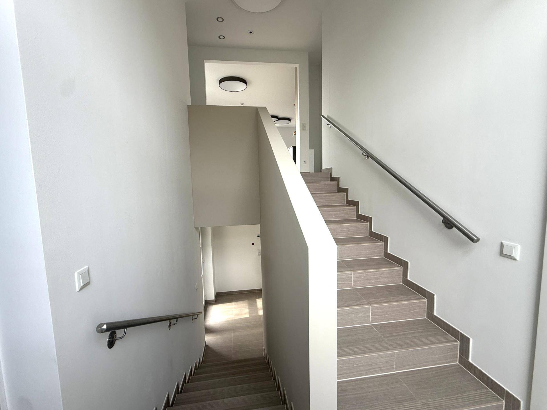 Geräumiges Treppenhaus mit modernen Fliesenstufen und elegantem Metallgeländer.