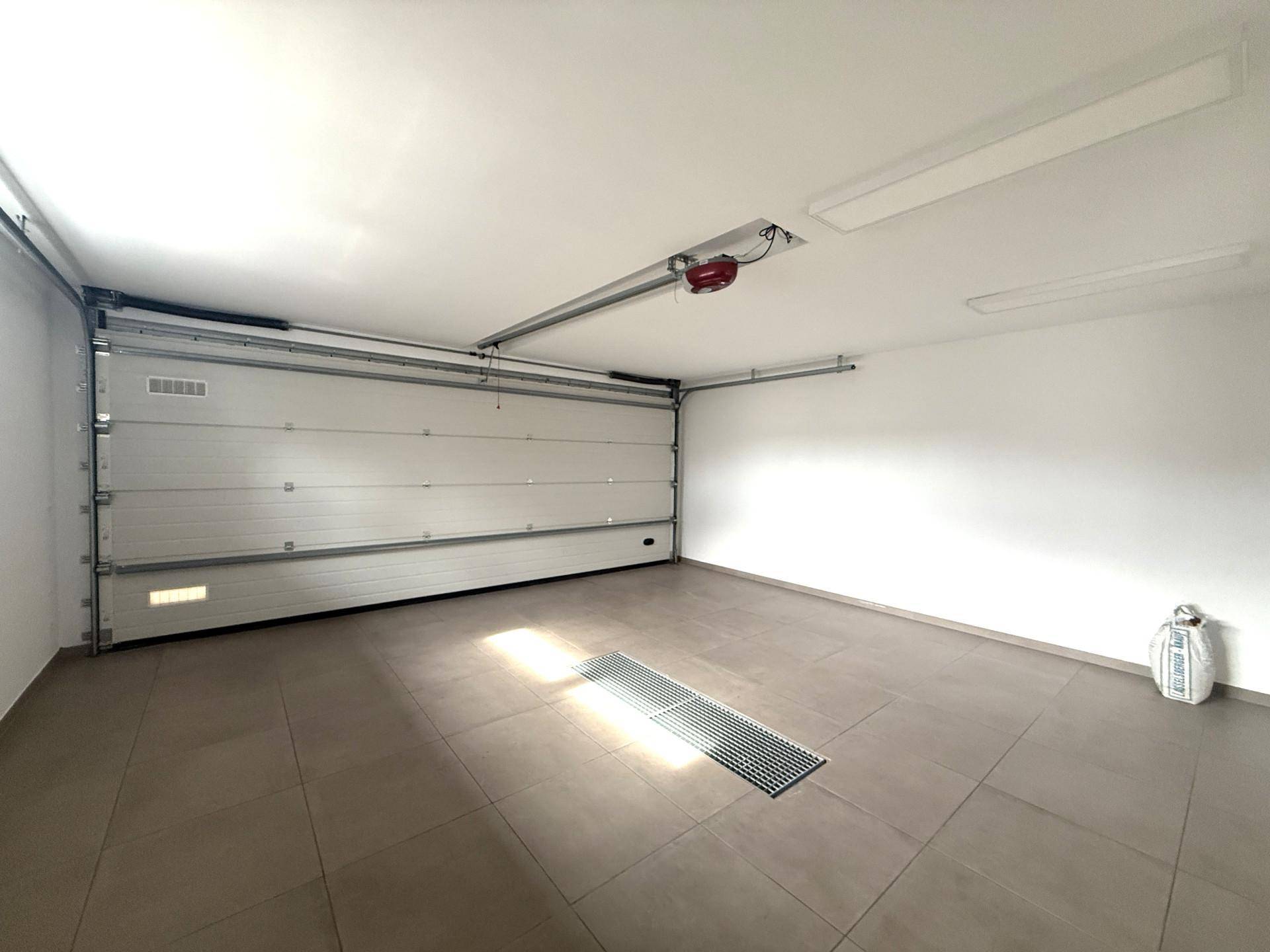 Geräumige Garage mit automatischem Tor und Fliesenboden, bietet Platz für ein Fahrzeug.