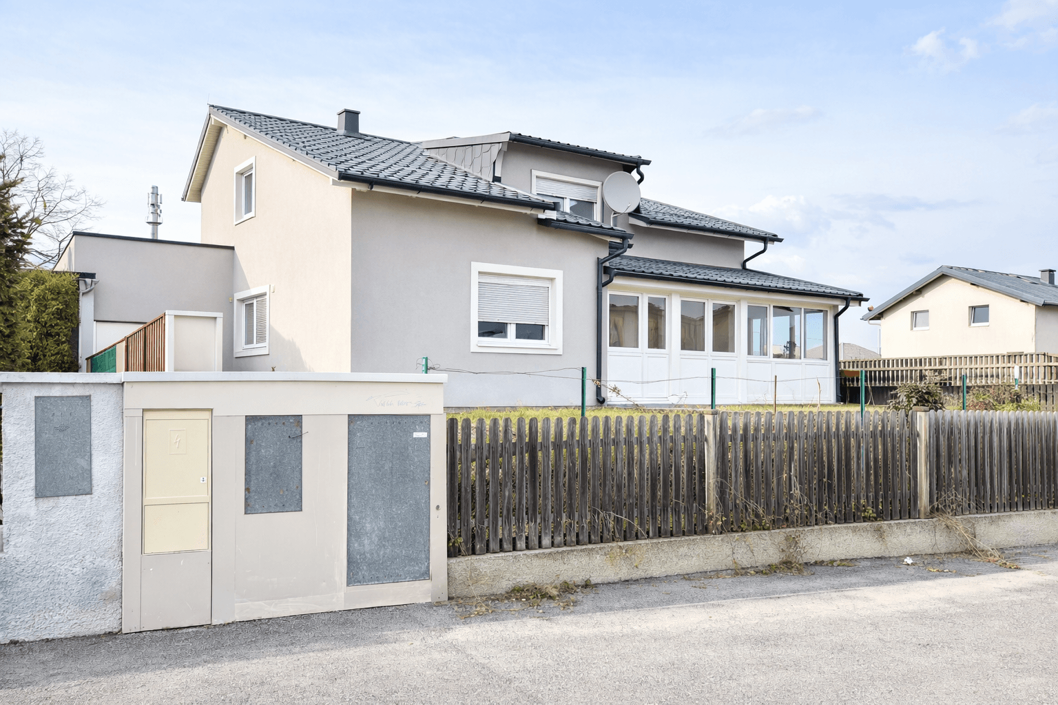Rückansicht des Hauses mit einem angebauten Wintergarten und gepflegtem Gartenbereich.