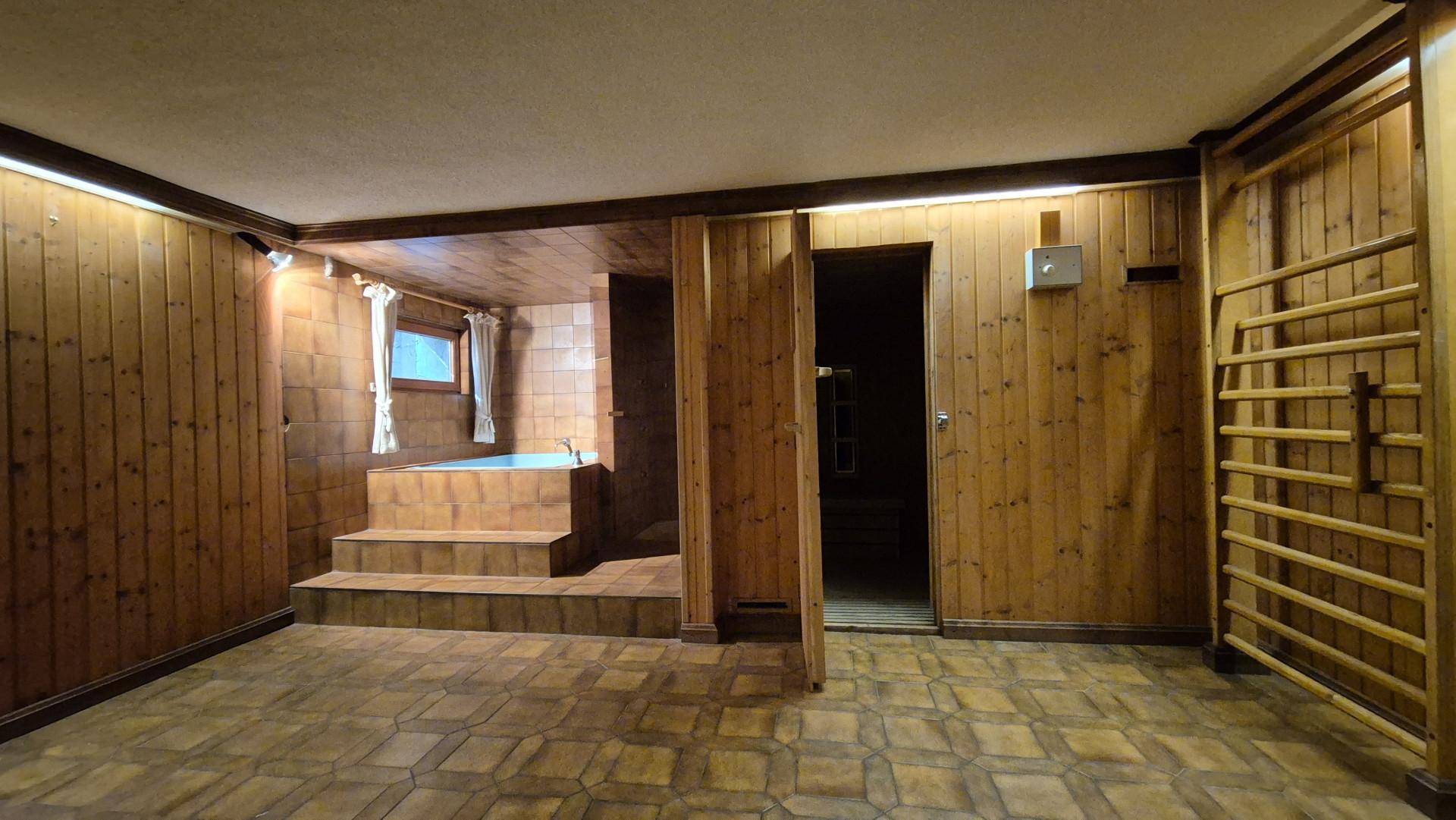 Wellnessbereich im Keller mit Whirlpool, Holzvertäfelung und Zugang zur Sauna.
