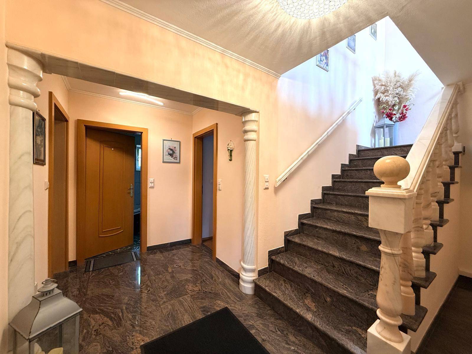 Elegantes Treppenhaus mit Granitstufen, Marmorsäulen und dekorativem Geländer, das die Etagen verbindet.