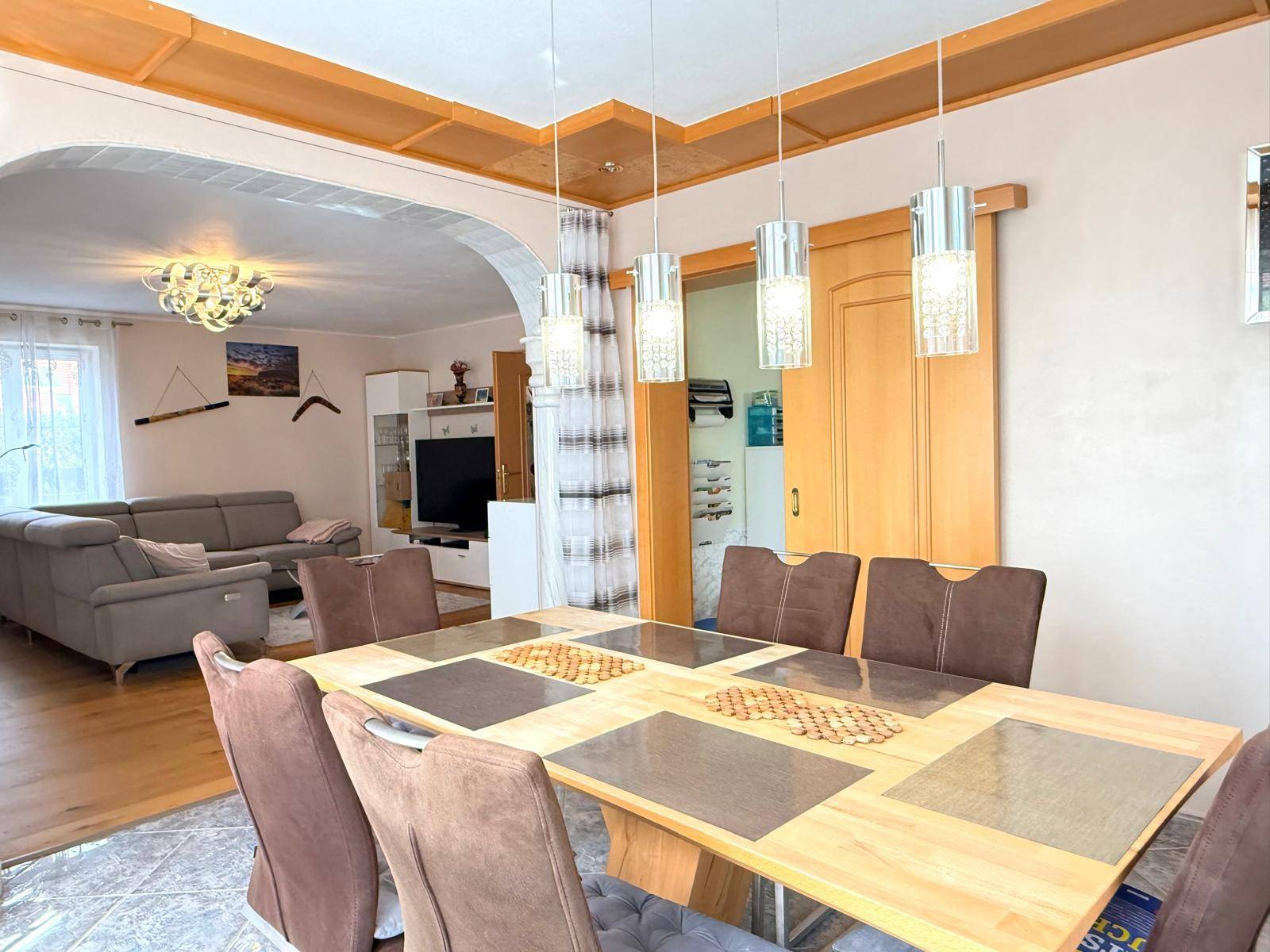 Geräumiger Essbereich mit großem Holztisch, modernen Hängelampen und offenem Übergang zum Wohnzimmer.